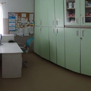 widok gabinetu doraźnej pomocy; na zdjęciu kozetka dla pacjenta, lodówka na leki, biurko pielęgniarskie z dwoma skomputeryzowanymi stanowiskami, szafa na leki i krzesło dla petenta, waga